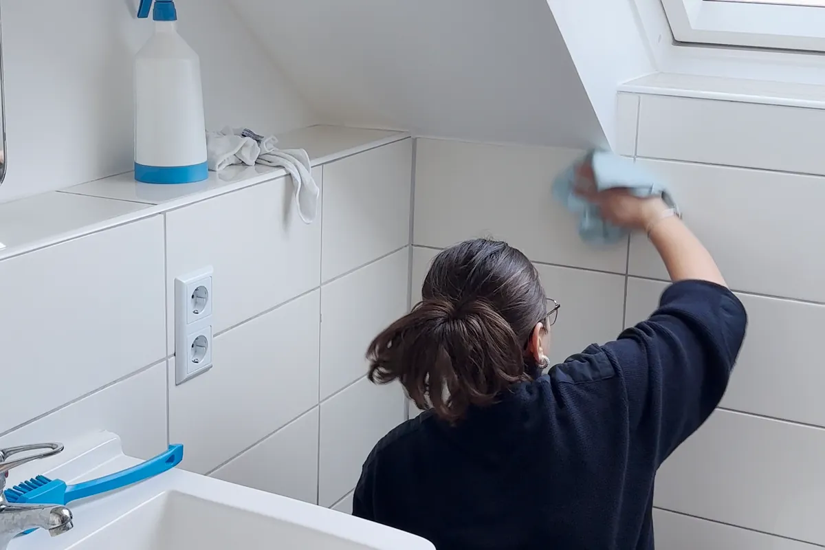 Eine GE+ES-Mitarbeiterin reinigt die Fliesen im Bad einer Neubauwohnung